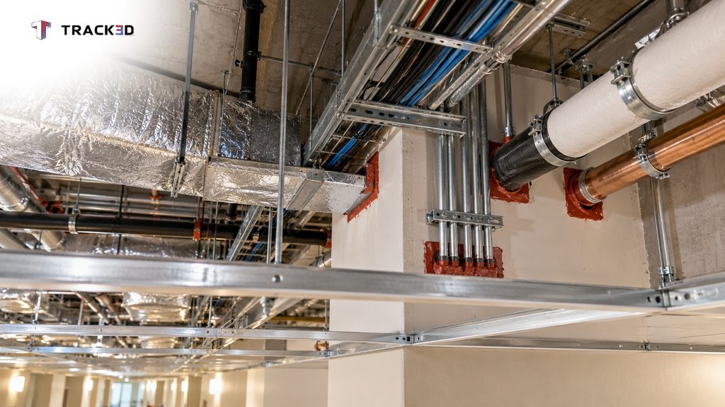 Open ceiling grid in a hospital hallway showing ductwork, pipes, and sealed penetrations through a rated wall